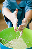 Little boy sprinkling flour into mixing bowl