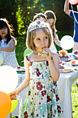 Girl wearing tiara and blowing party horn blower at outdoor party