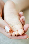 Woman's hand holding baby's foot