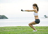 Young woman working out with weights, outdoors