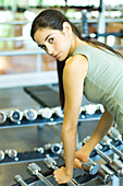 Woman picking up weights, looking over shoulder at camera