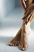 Die Hand einer Frau berührt ihre nackten Füße