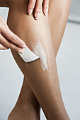 Woman applying hair removal cream to leg