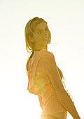 Woman standing in sun, looking over shoulder