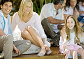 Girl splashing water, family relaxing in background