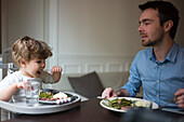 Father and toddler son eating dinner together