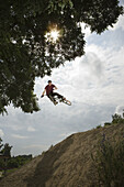 A BMX rider in mid-air at the top of a mud slope