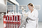 A row of vials holding blood and a lab technician working in background, focus on foreground
