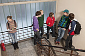 Five teenage boys talking and ignoring a teenage girl in a school stairwell