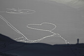 A heart shape  and smiley face stamped out in the snow by footprints