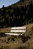 A wooden bench seat in a mountain setting