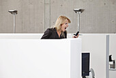 A woman screaming into a mobile phone in an office cubicle