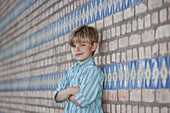 A boy leaning against a wall and smirking