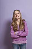 A laughing teenage girl with arms crossed, portrait, studio shot