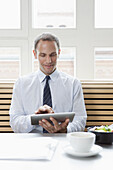 A businessman using a digital tablet on his lunch break