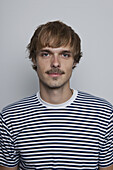 A young man with a mustache wearing a striped t-shirt