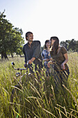 Three friends amongst the timothy grass walk with bike