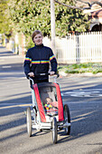 A woman walking on a street and pushing a baby stroller