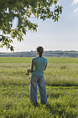 A mother standing in a field while holding her baby and looking at the view