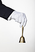 A butler ringing a hand bell for service, focus on hand