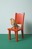 An imitation bird sitting on a miniature chair