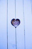 Close-up of woman puckering lips through heart shape wood