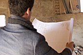 An architect reviewing blueprints at a building site