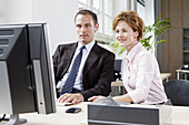 A businessman and businesswoman working together at a computer