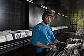 A young man in a record shop, looking at camera