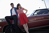 A cool, rockabilly couple leaning against a vintage car