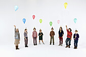 A group of mostly bored looking kids holding balloons and wearing party hats