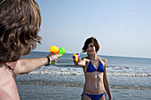 A young couple playing with squirt guns at the beach