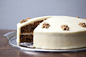A carrot cake with a slice missing for sale in a cafe