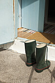 Two wellington boots in front of an open door