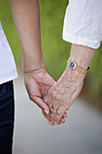 Detail einer älteren Frau und einer jungen Frau, die sich an den Händen halten