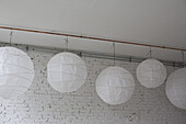 Five white round paper lanterns hanging in a row