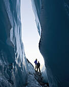Two women stand looking into crevasse at Worthington Glacier, Alaska, USA