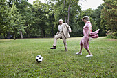 Senior man and woman play football in the park