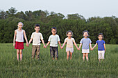 Portrait of children holding hands in a field