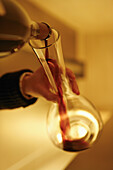 Detail of a person pouring red wine into a decanter