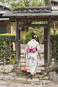Full length rear view of woman in traditional wear entering gateway