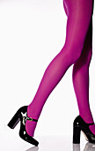 Side view of a woman wearing pink tights and high heels, low section