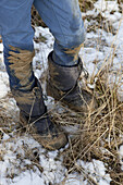 Low section of boy with dirty jeans and boots during winter