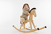 A baby girl on a rocking horse