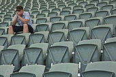 Sad man sitting alone in empty stadium