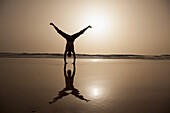 Full length of silhouette man performing handstand at beach