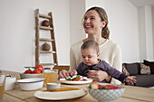 Happy woman looking away while sitting with baby girl at home