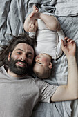Portrait of smiling father with baby girl lying in bed