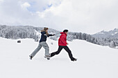Full length side view of couple running in snow