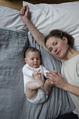 High angle portrait of mother with baby girl lying on mattress